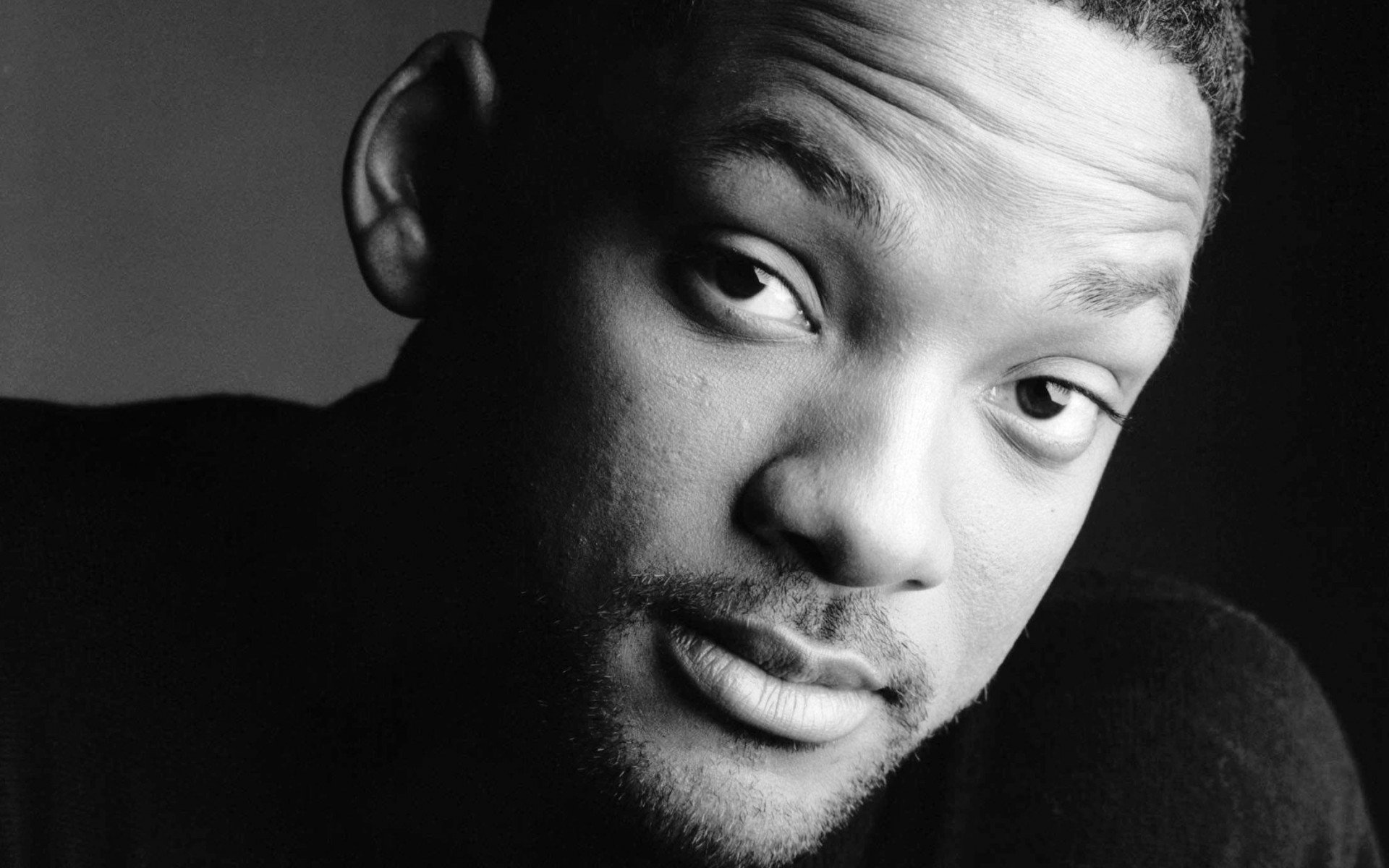 Close-up black and white HD desktop wallpaper of celebrity Will Smith with a thoughtful expression against a dark background.