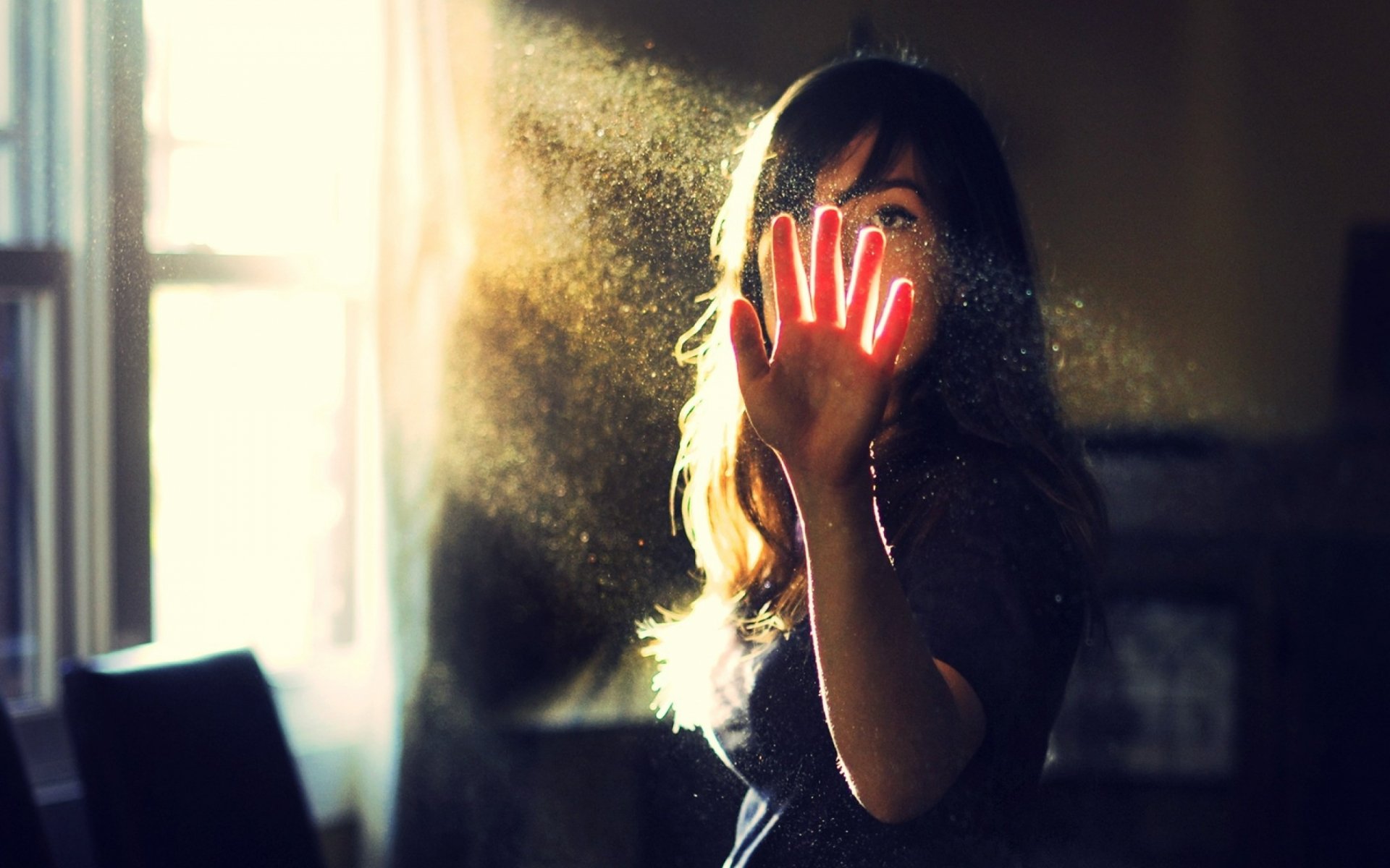 HD desktop wallpaper of a pretty woman reaching out with her hand, illuminated by soft sunlight streaming through a window.