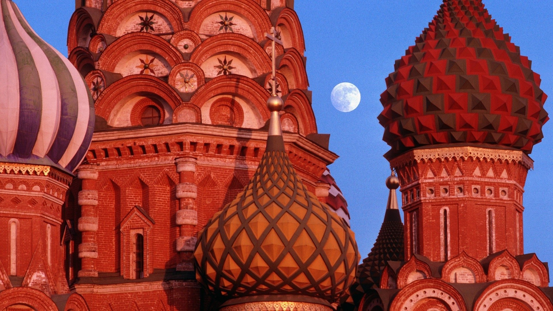 HD desktop wallpaper showcasing the vibrant domes of Saint Basil's Cathedral against a clear blue sky with the moon visible.