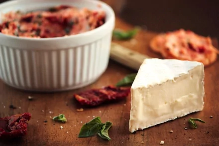 HD PC desktop wallpaper and background: food close-up of a creamy cheese wedge on a wooden board, scattered herbs, sun-dried tomatoes and a ramekin of spread.
