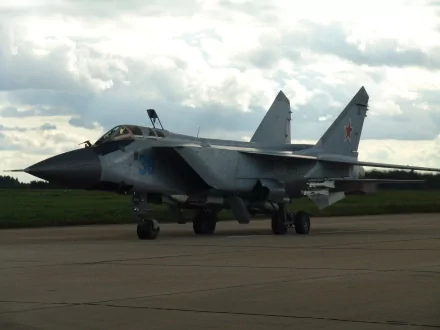 HD desktop wallpaper featuring a Mikoyan MiG-31 military aircraft on a runway under a cloudy sky.