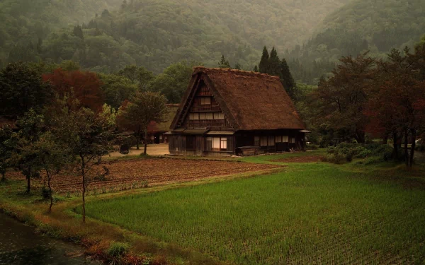 A serene farm scene featuring a traditional thatched house, surrounded by lush green fields and distant mountains, creating a tranquil atmosphere for a stunning HD desktop wallpaper.