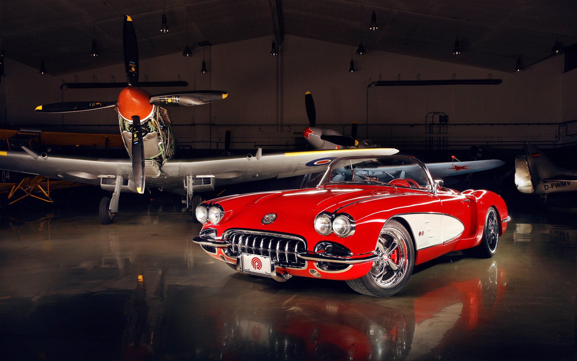 A vibrant red Chevrolet Corvette parked inside an aircraft hangar, with vintage planes in the background, captured in HD for a PC desktop wallpaper.