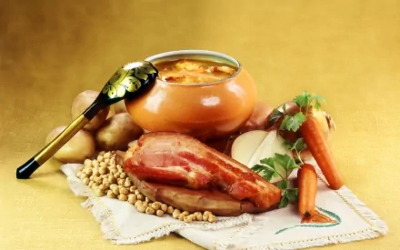 HD PC desktop wallpaper and background showing food: a hearty bowl of soup with ladle, smoked ham, peas, potatoes and carrots on a cloth against a warm golden backdrop.