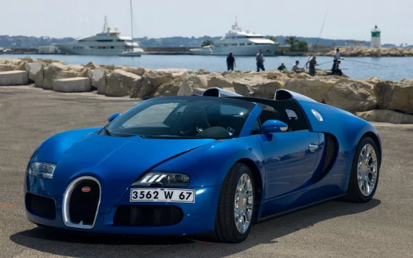 A stunning Bugatti Veyron in striking blue, parked by the waterfront, with luxury yachts in the background, serves as an impressive HD PC desktop wallpaper.