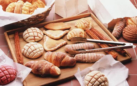 HD desktop wallpaper showing an assortment of freshly baked pastries and bread arranged in baskets and boxes, highlighting food and baking themes.