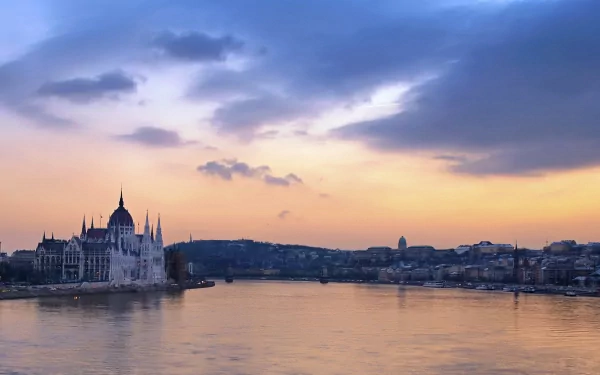 HD wallpaper showcasing a serene sunset over Budapest, Hungary, with the iconic Hungarian Parliament building silhouetted against a colorful sky along the Danube River.