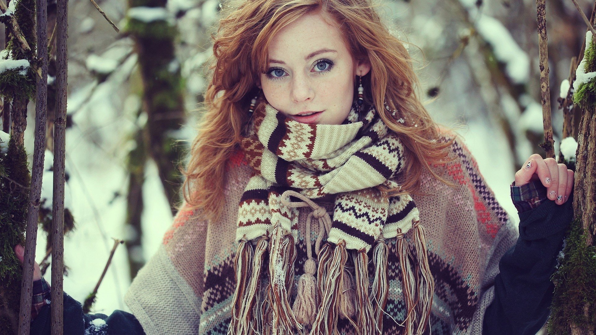 A woman stands in a snowy forest wearing a patterned scarf and warm clothing. Her serene expression captures a contemplative mood. This is an HD desktop wallpaper and background.