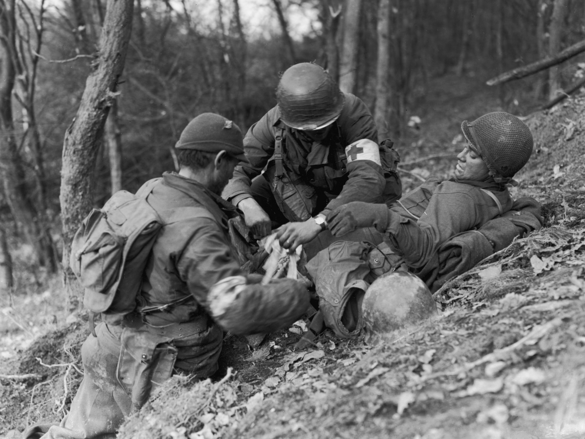 Black and white 4K Ultra HD desktop wallpaper depicting World War II military medics tending to a wounded soldier in a forested area.