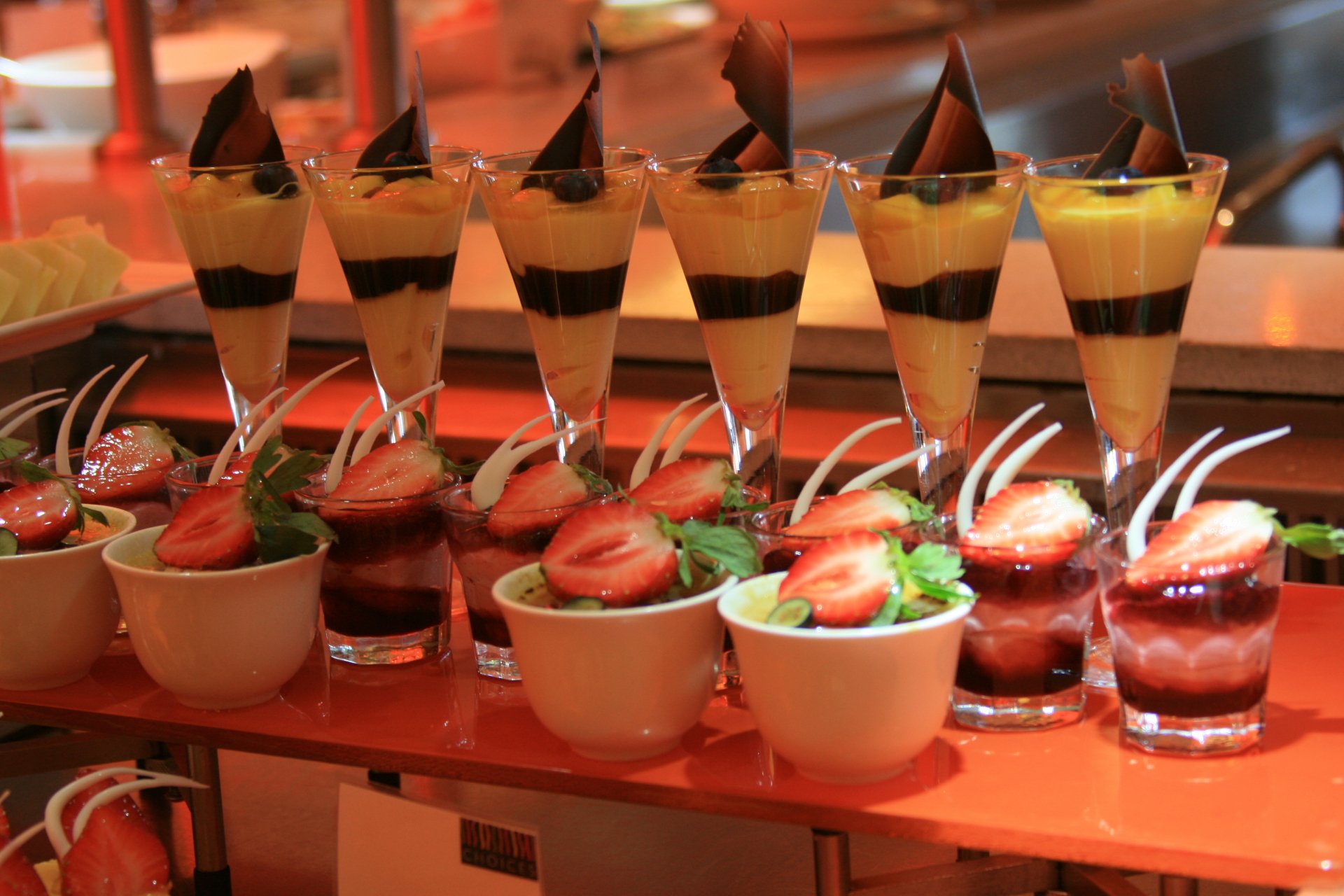 A vibrant display of desserts featuring layered parfaits and fruit-topped cups, set against a warm backdrop, making for an enticing 4K Ultra HD wallpaper for food lovers.