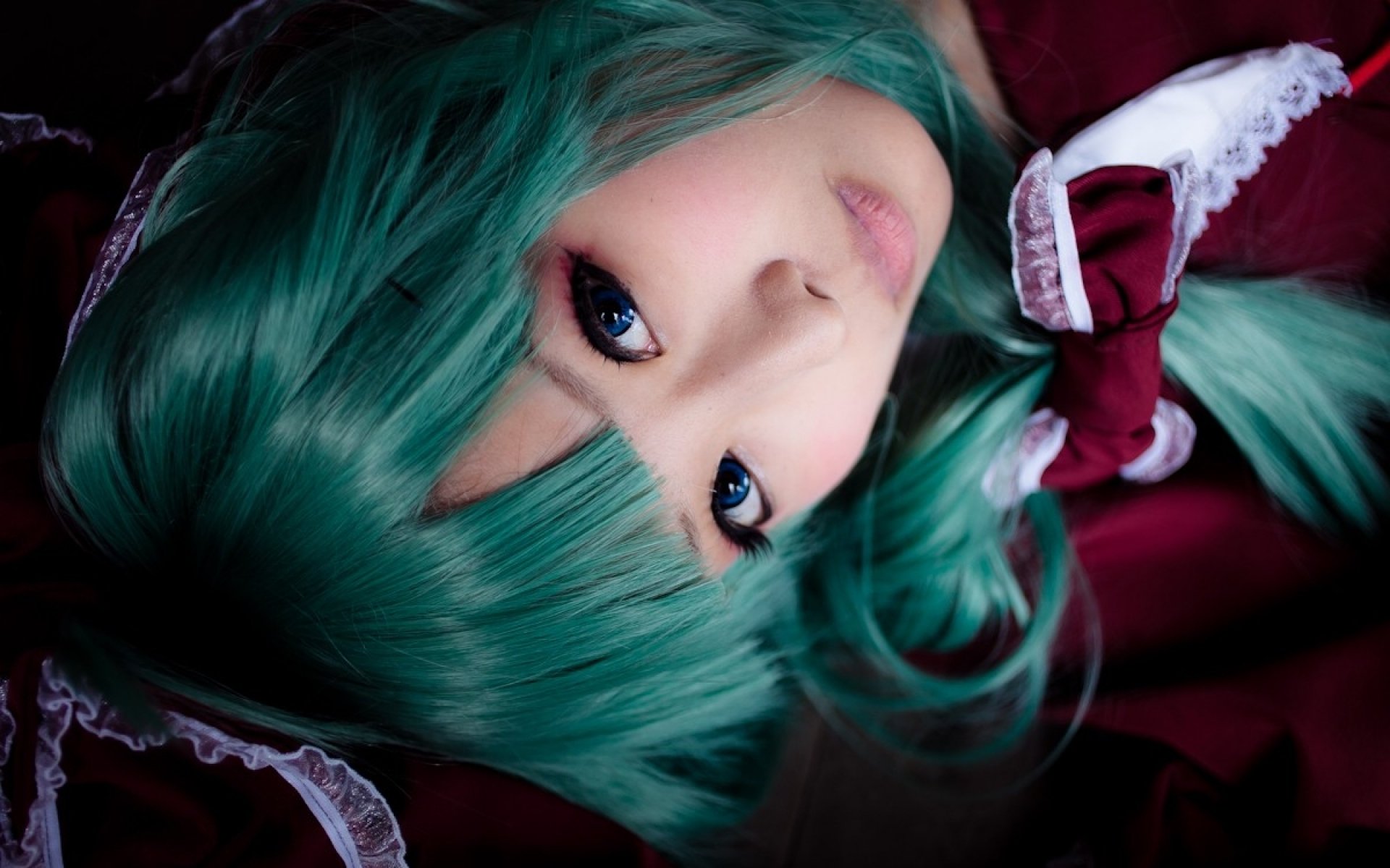 HD desktop wallpaper of an Asian woman cosplaying Hina Kagiyama from Touhou, featuring vibrant teal hair and detailed costume elements.