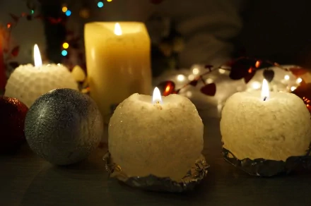 4K Ultra HD photography of lit candles, including heart-shaped and spherical designs, creating a warm, cozy atmosphere with soft glowing light on a desktop wallpaper.