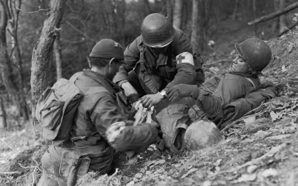 Black and white 4K Ultra HD desktop wallpaper depicting World War II military medics tending to a wounded soldier in a forested area.