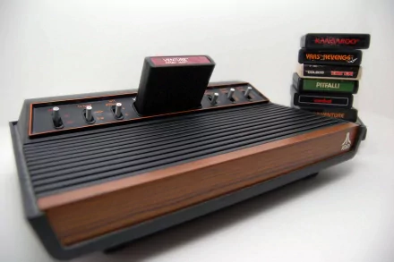 Atari 2600 video game console with cartridge inserted and stack of game cartridges, presented as a 2K Quad HD PC desktop wallpaper/background.