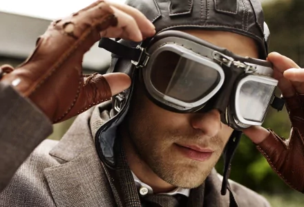 HD desktop wallpaper featuring a man in vintage aviator gear, including goggles and leather gloves, adjusting his goggles with a focused expression. The tag indicated is Beautiful.