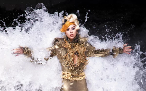 HD PC desktop wallpaper featuring Lady Gaga in a dramatic gold outfit with water splash effects, highlighting her iconic presence in music.