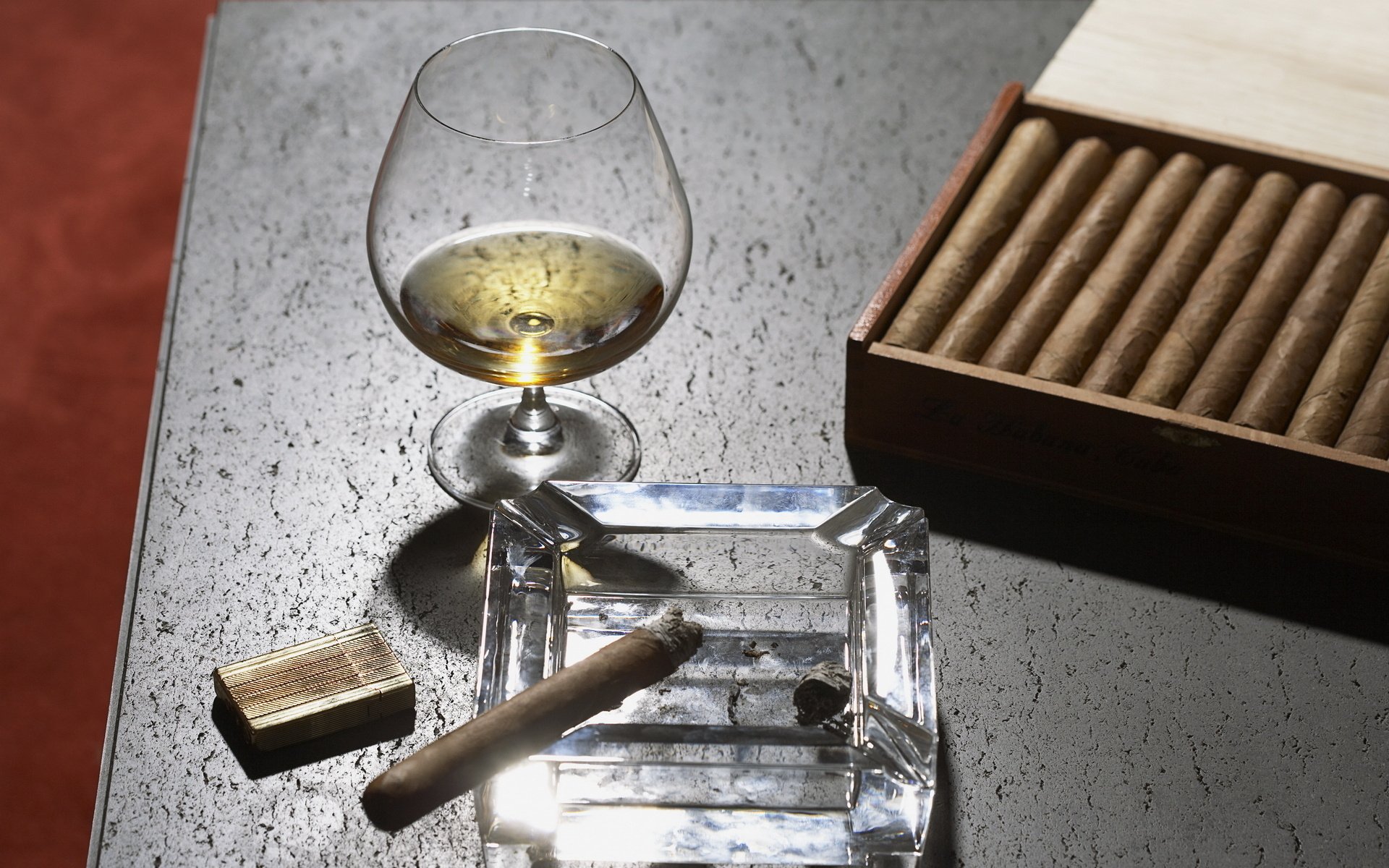 HD desktop wallpaper showing a glass of whisky, a cigar in a glass ashtray, and a box of cigars on a textured surface.