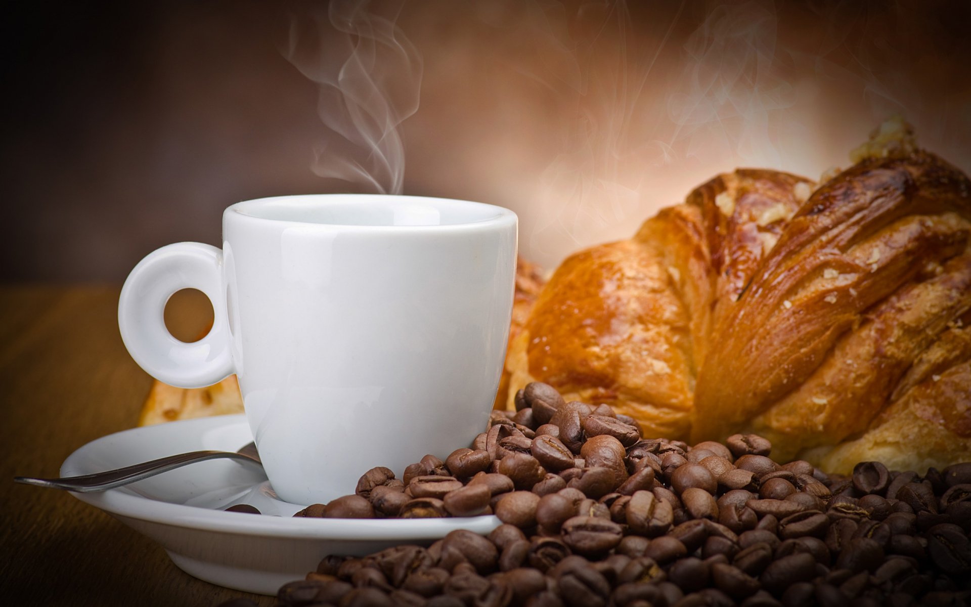 2K Quad HD PC desktop wallpaper: steaming coffee in a white cup with scattered coffee beans on a saucer and a flaky croissant against a warm, blurred background (food, coffee).