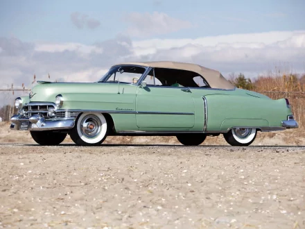 Classic vehicle: mint-green Cadillac Sixty-Two convertible on a sandy shore beneath a cloudy sky — HD PC desktop wallpaper/background.