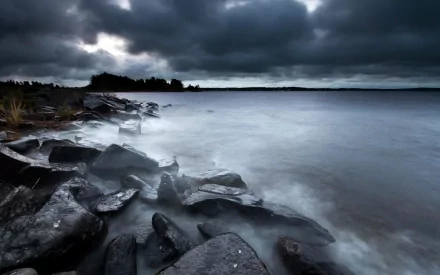 HD PC desktop wallpaper background: stormy nature scene with dark brooding clouds over a rocky shoreline and misty waves.