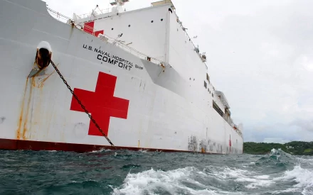HD desktop wallpaper of the USNS Comfort (T-AH-20), a U.S. Navy hospital ship, showing its large hull with the red cross symbol on the ocean.