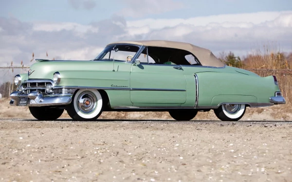 Classic vehicle: mint-green Cadillac Sixty-Two convertible on a sandy shore beneath a cloudy sky — HD PC desktop wallpaper/background.