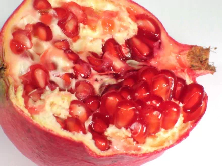 Food-themed HD PC desktop wallpaper/background: close-up of a halved pomegranate showing glossy red arils and creamy white pith.