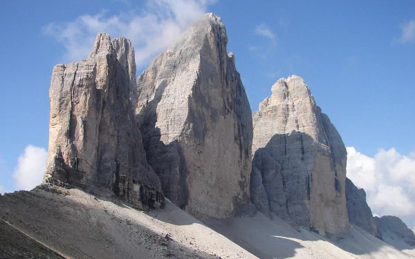 HD PC desktop wallpaper background of nature: Tre Cime di Lavaredo's sunlit limestone peaks rising against a bright blue sky.