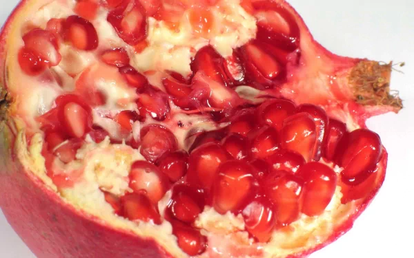 Food-themed HD PC desktop wallpaper/background: close-up of a halved pomegranate showing glossy red arils and creamy white pith.