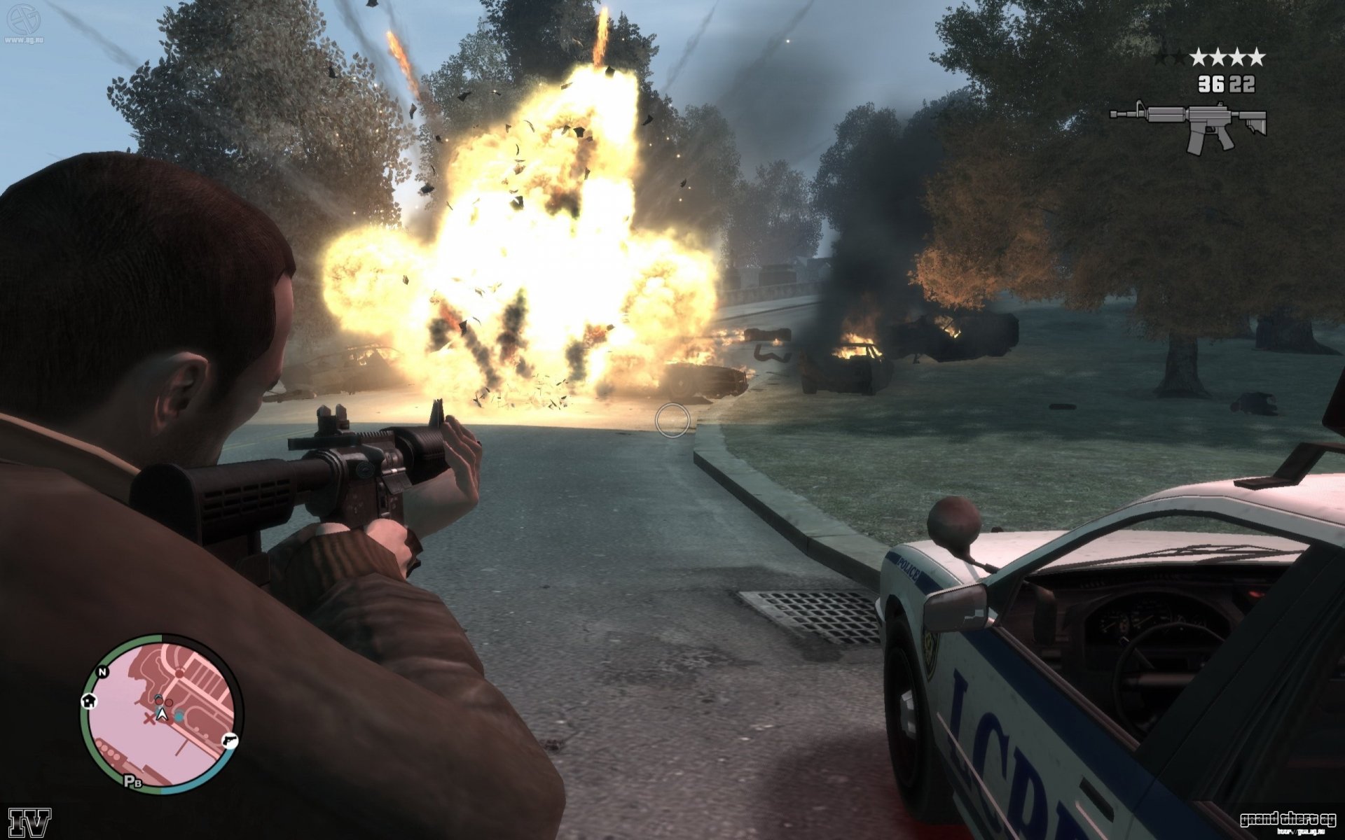 HD PC desktop wallpaper featuring an intense action scene from the video game Grand Theft Auto IV, showing a character firing a weapon near an exploding police car.