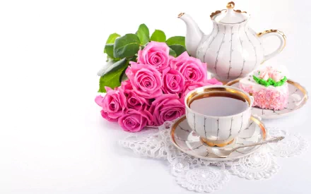 A teapot, cup of tea, and a slice of cake sit beside a bouquet of pink roses, beautifully arranged on a lace doily, creating a serene food and tea-themed desktop wallpaper.