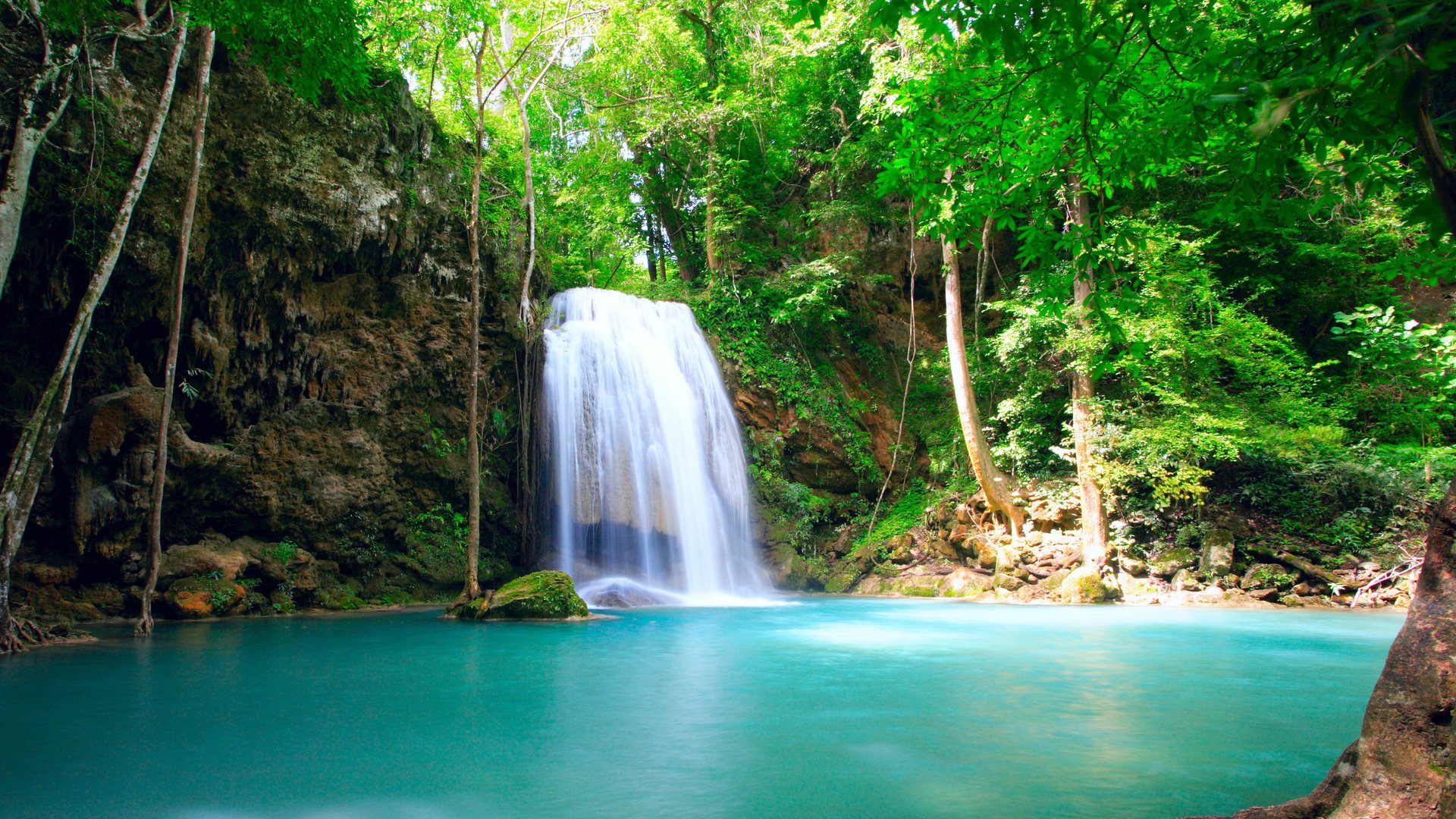 HD PC desktop wallpaper featuring a serene waterfall cascading into a turquoise pool surrounded by lush green forest in a vibrant natural setting.