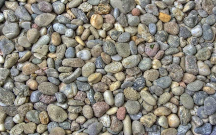 Nature stone texture of smooth multicolored river pebbles, 2K Quad HD PC desktop wallpaper and background.