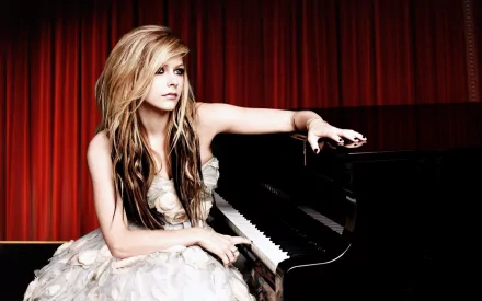 HD desktop wallpaper featuring Avril Lavigne in a white dress, leaning on a grand piano against a backdrop of red curtains. The image captures a musical theme.