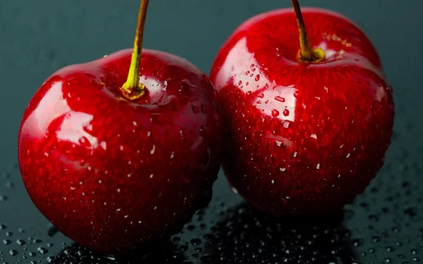 HD desktop wallpaper featuring two glossy red cherries with water droplets against a dark, reflective background.