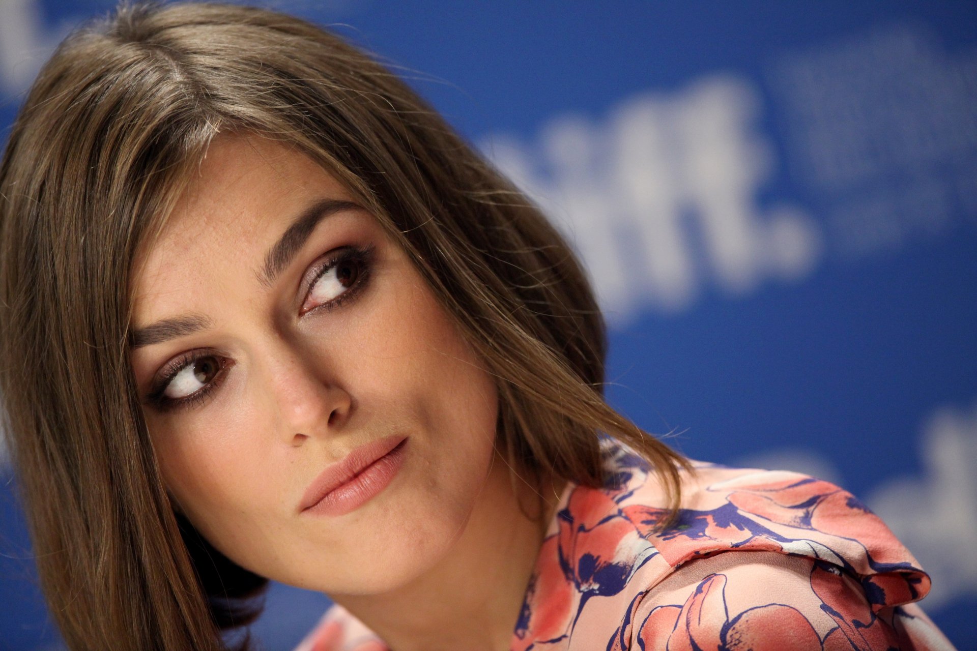 4K Ultra HD desktop wallpaper featuring a close-up portrait of celebrity Keira Knightley with a soft expression against a blue backdrop.