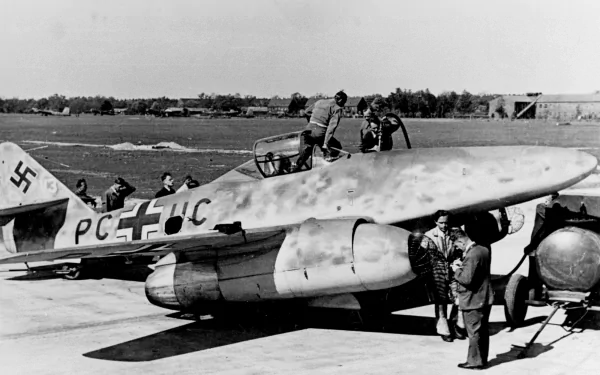 Black and white HD desktop wallpaper showing a World War II Messerschmitt Me 262 military jet on the runway with personnel around it.