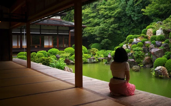 A high-definition wallpaper features an Asian woman sitting in a serene garden, surrounded by lush greenery and a tranquil pond. The peaceful atmosphere sets a calming mood.