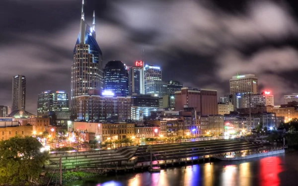 HD desktop wallpaper showcasing the vibrant nighttime skyline of man-made structures in Nashville, with illuminated buildings reflecting on the water.