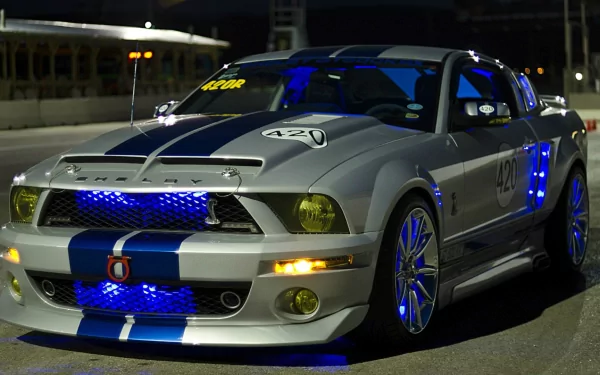 A high-definition desktop wallpaper featuring a Ford Mustang Shelby GT500 with blue accents illuminated, parked under nighttime lighting.