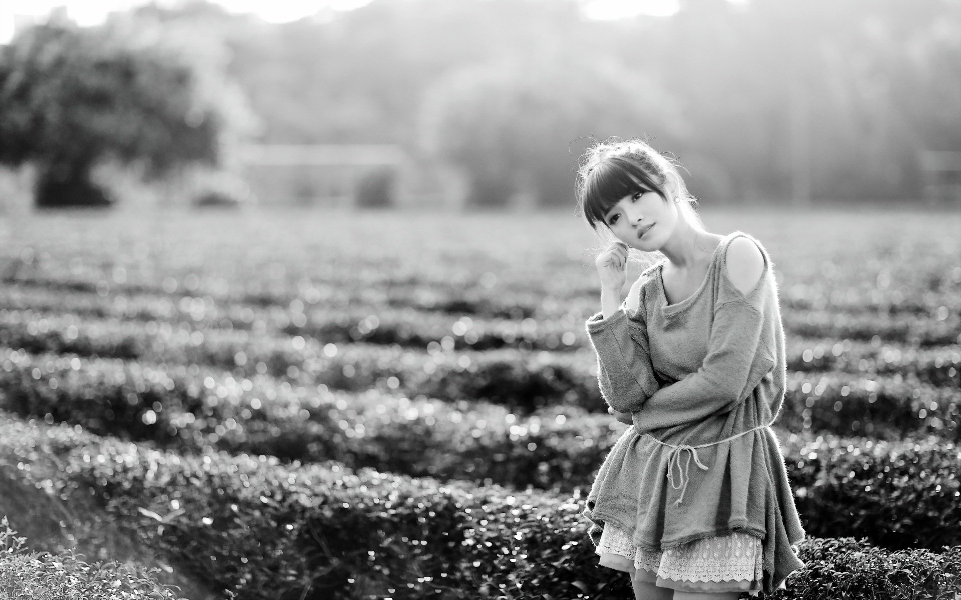 Black and white image of a woman in a thoughtful mood, standing in a field. This HD desktop wallpaper captures a serene and contemplative atmosphere.