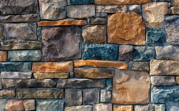 Textured slate wall featuring various shades of gray, brown, and blue stones. High-definition image serves as an appealing desktop wallpaper and background.