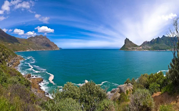 A stunning HD desktop wallpaper of a scenic coastline, featuring vibrant blue waters, lush greenery, and distant mountains under a clear sky. Nature's beauty captured in high definition.