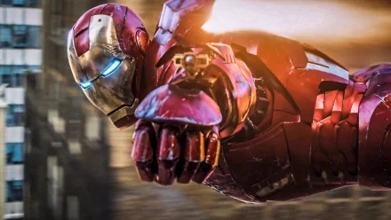 HD desktop wallpaper featuring Iron Man flying with a powerful stance and glowing blue eyes. The background shows a blurred urban setting, emphasizing the action and dynamism of the scene.