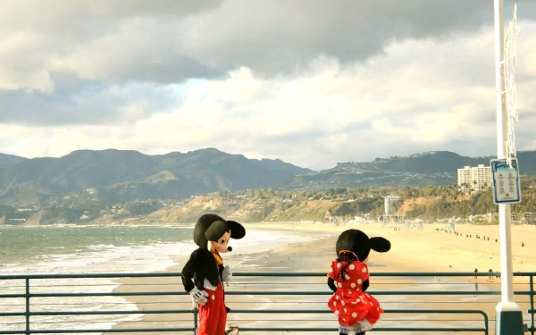 Funny cartoon HD PC desktop wallpaper and background: two cartoon mice—one in a red polka-dot dress—chat on a pier overlooking a sunlit beach, ocean and distant mountains.