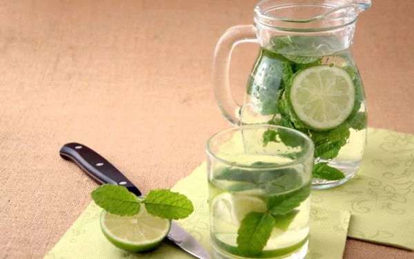 HD PC desktop wallpaper featuring fresh lime slices and mint leaves in a glass pitcher and a glass, set on a light green cloth with a knife nearby.