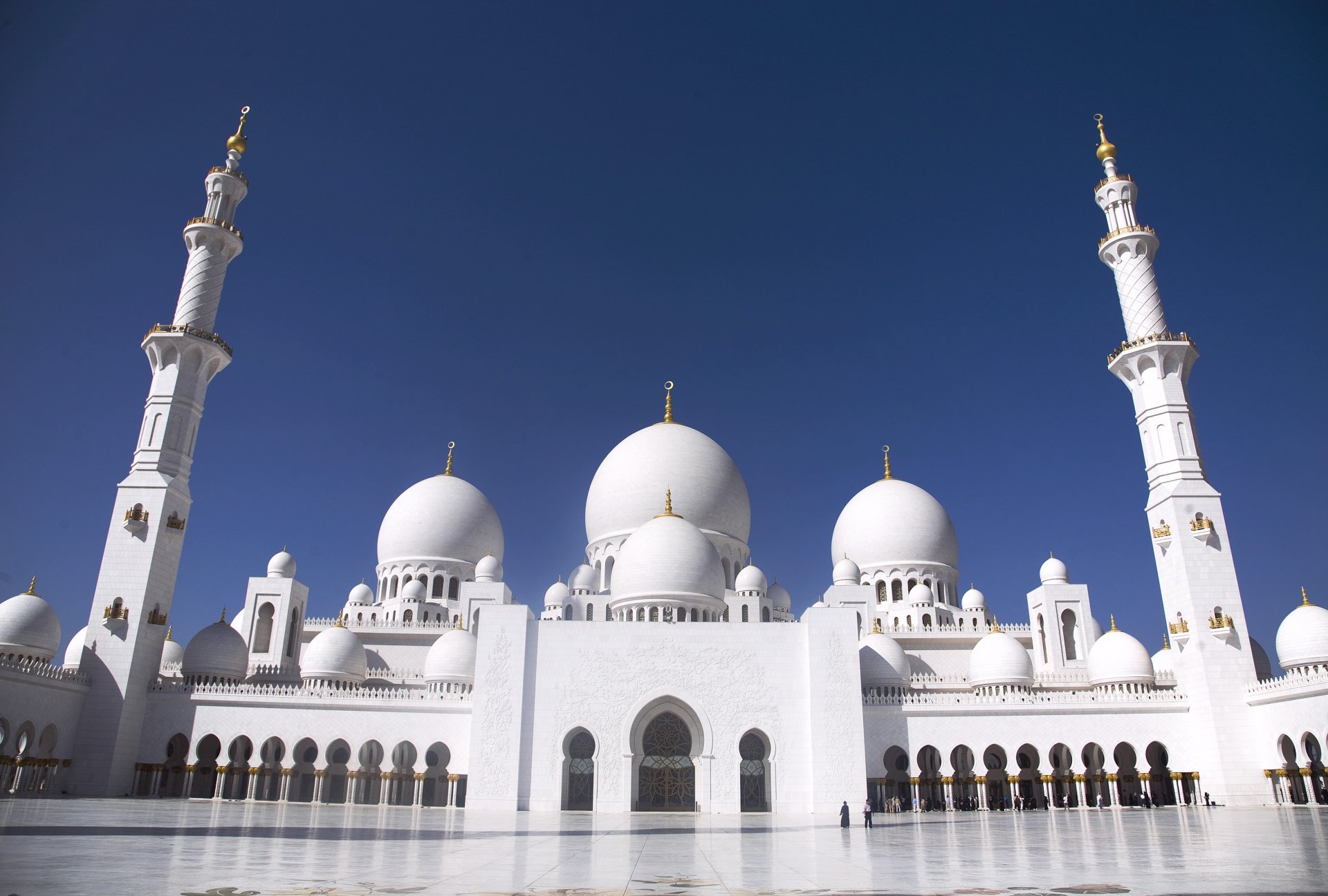 HD desktop wallpaper of the Sheikh Zayed Grand Mosque showcasing its majestic white domes and minarets under a clear blue sky, highlighting its religious architecture.