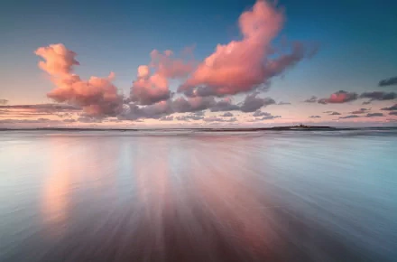 HD desktop wallpaper featuring a serene pastel-colored beach scene with soft clouds reflecting over calm waters under a peaceful sky.