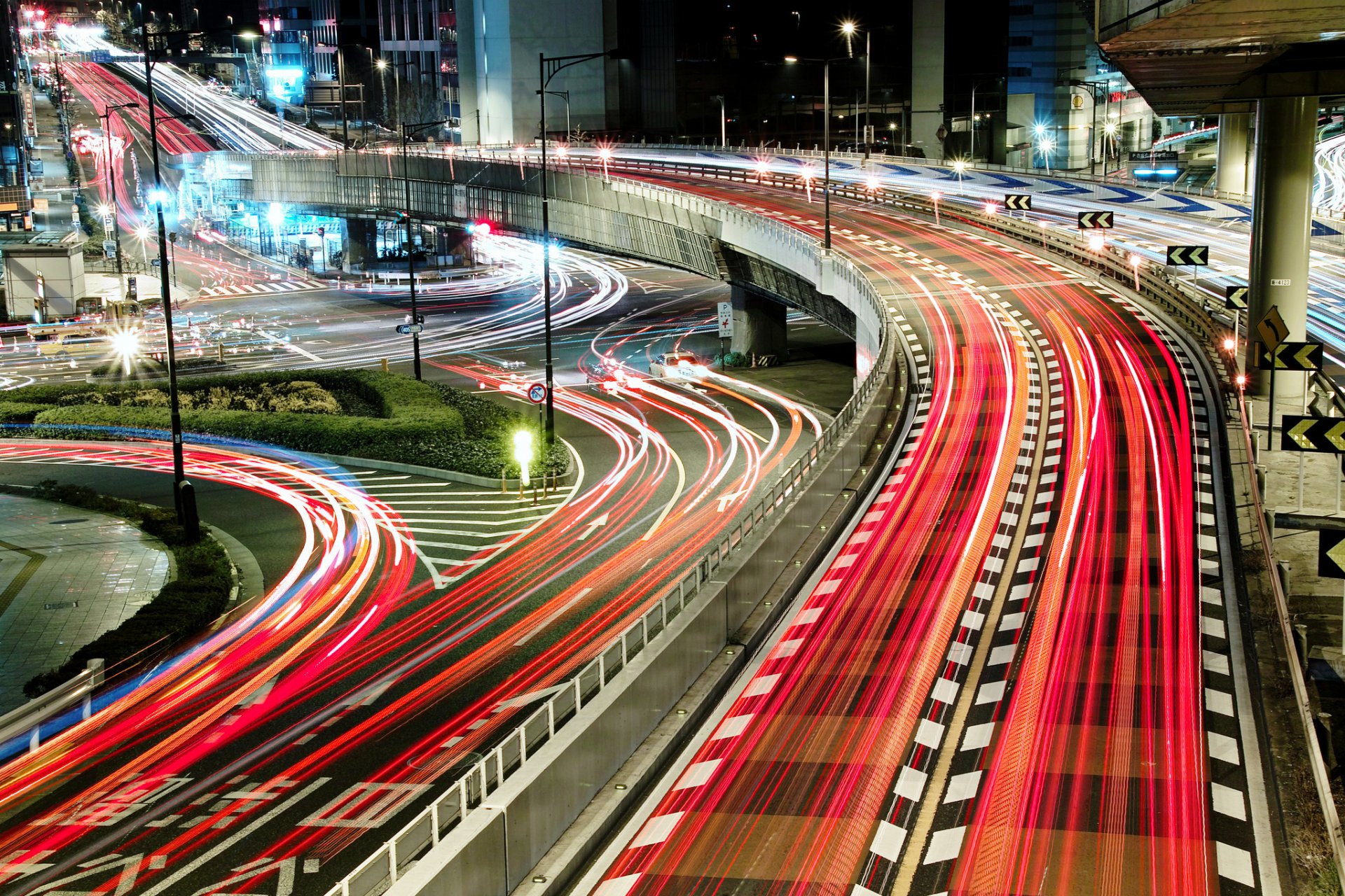 Time-lapse photography captures vibrant light trails from vehicles on a busy multi-level highway at night, creating a dynamic HD PC desktop wallpaper background.