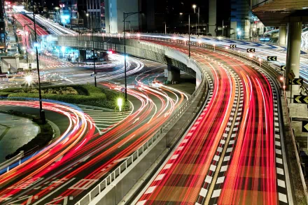 Time-lapse photography captures vibrant light trails from vehicles on a busy multi-level highway at night, creating a dynamic HD PC desktop wallpaper background.